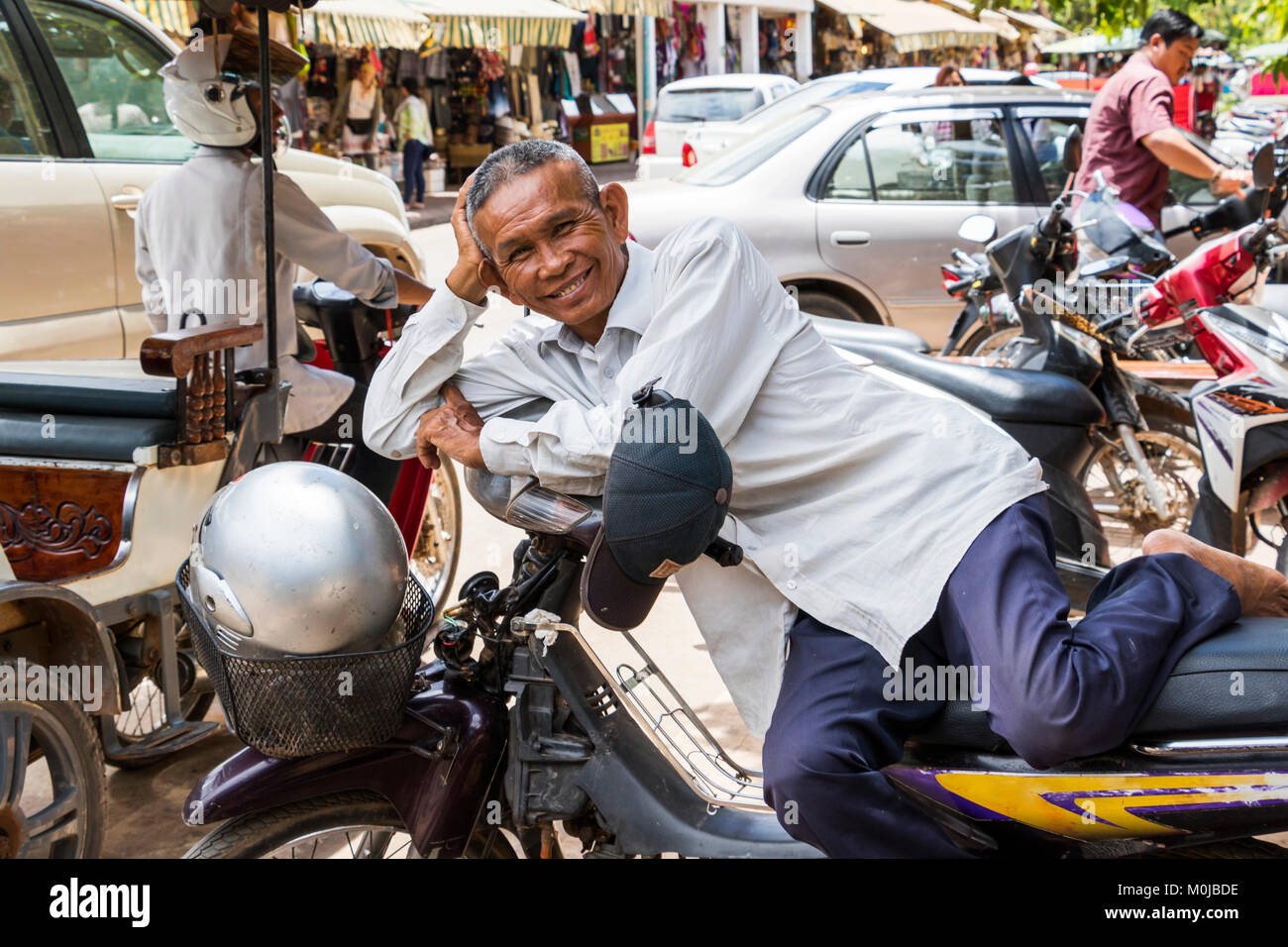 Cambodian man resting on a motorcycle; Siem Reap, Cambodia Stock Photo -  Alamy