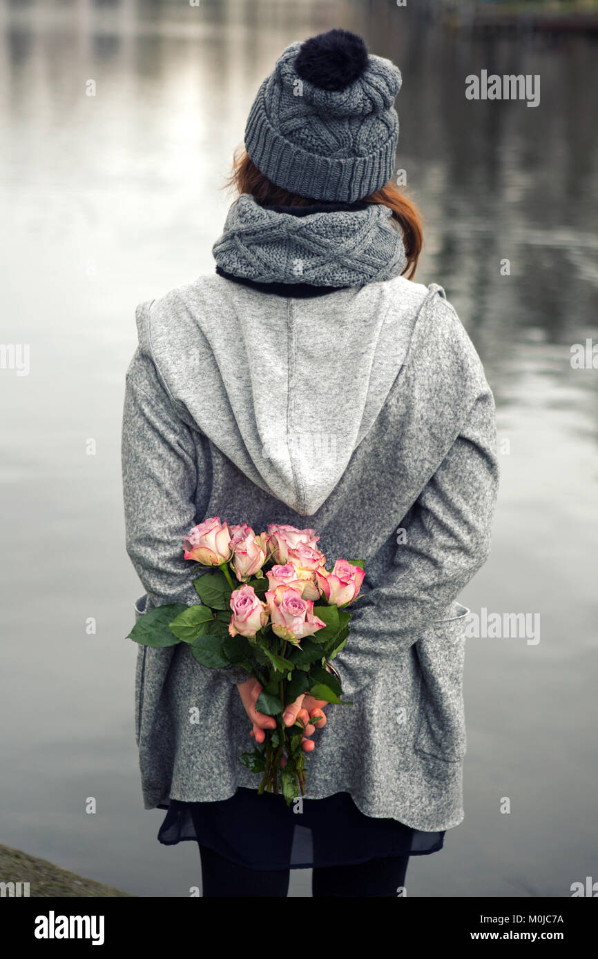 young woman standing by the water with bouquet of pink roses Stock ...
