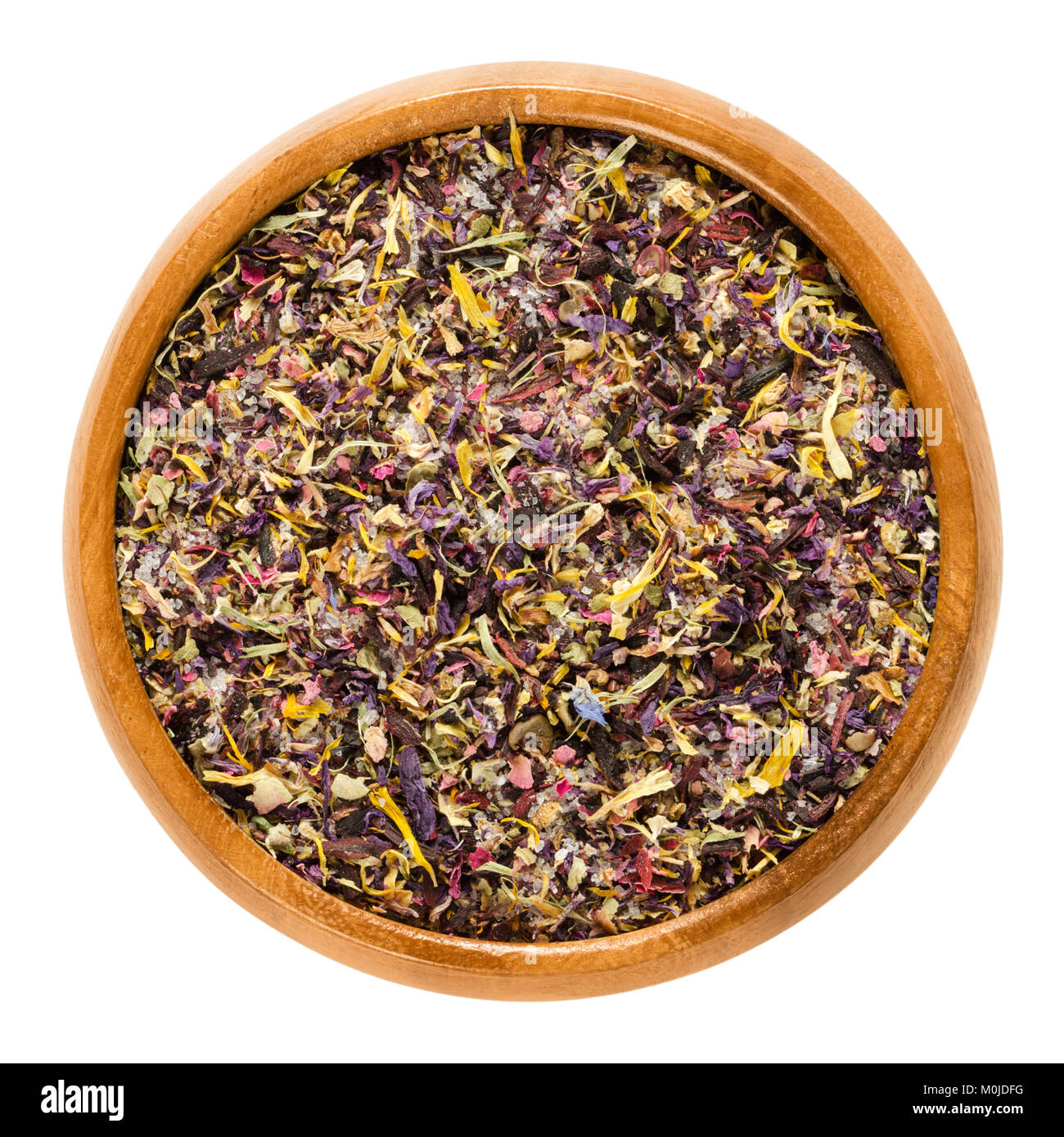 Blossom salt in wooden bowl. Desert salt with colorful dried flower blossoms of hibiscus, marigold, rose, mallow and cornflower. Stock Photo