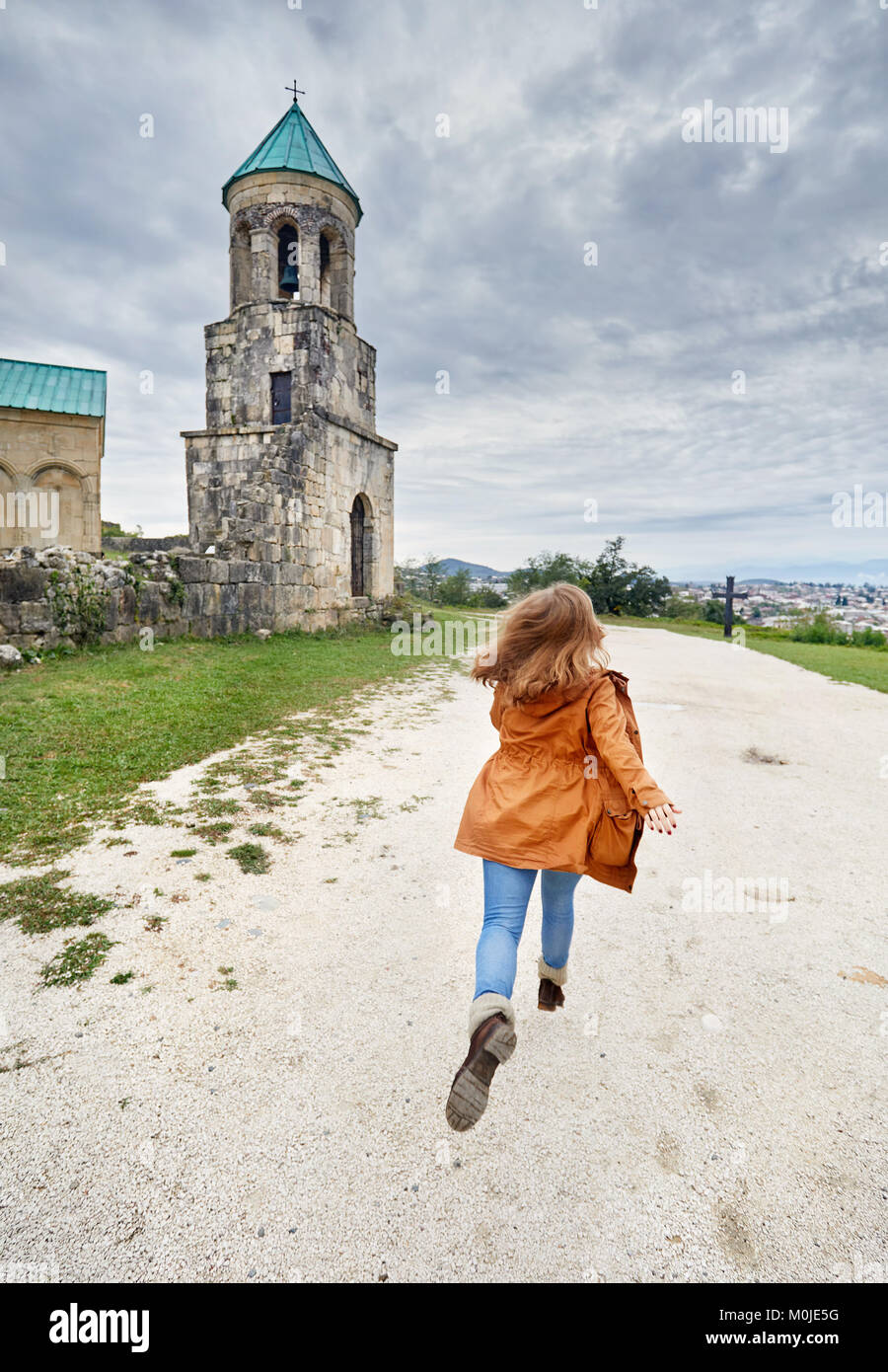 Woman running to the Chapel tower of Bagrati church at overcast sky in Kutaisi, Georgia Stock Photo