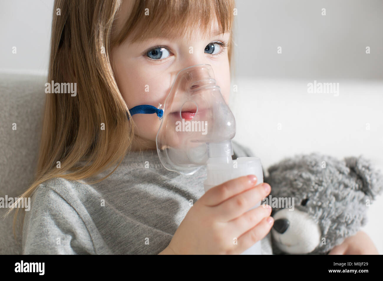 Little girl making inhalation with nebulizer at home. child asthma inhaler inhalation nebulizer steam sick cough concept Horizontal Stock Photo