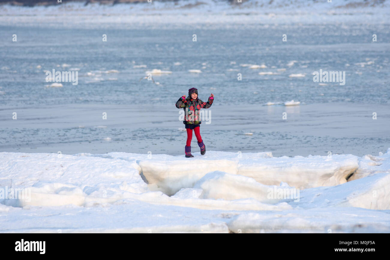 A young girl dances on the ice at Corporation Beach in Dennis, Massachusetts on Cape Cod, USA on a January day Stock Photo