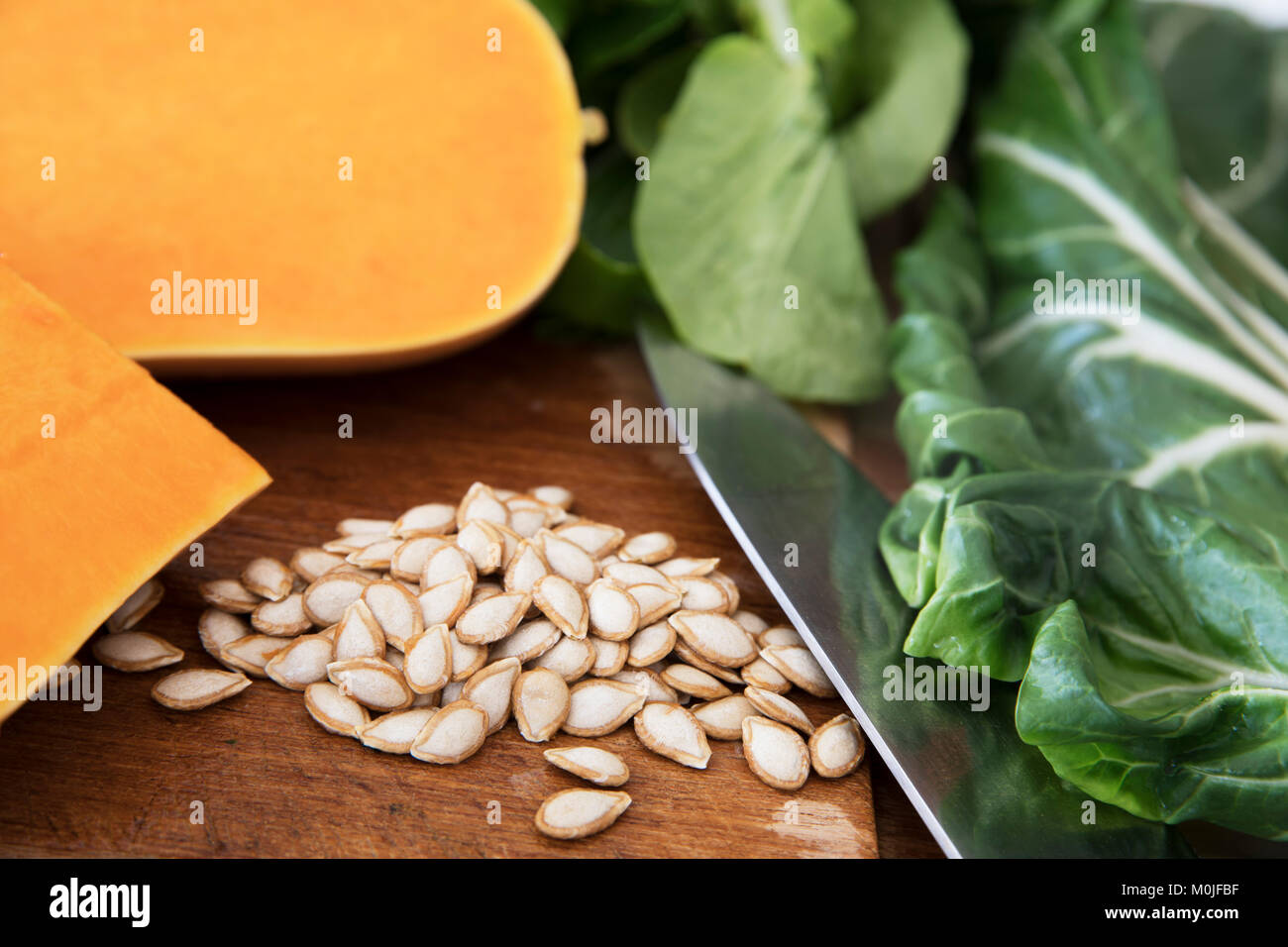 Butternut squash seeds on a cutting board with a knife, pieces of