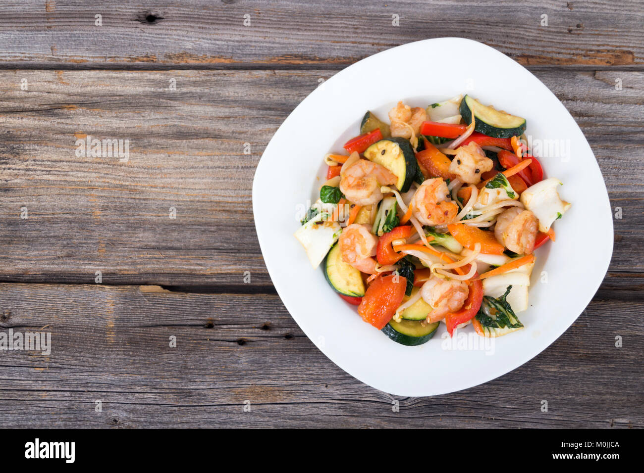 Shrimp stir fry  with vegetables over wood background Stock Photo