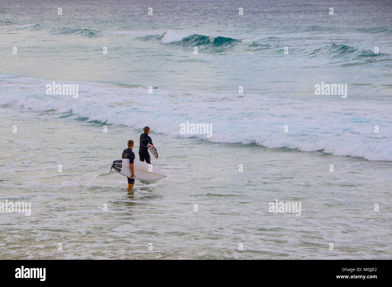 Two surfer walk out into the water - at Kirra Beach, Queensland, Australia Stock Photo