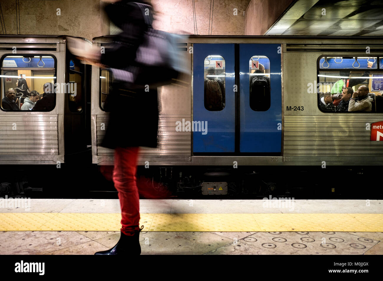 people waiting for the train at a subway station platform, train arrives showing  a  blurry speed. Stock Photo