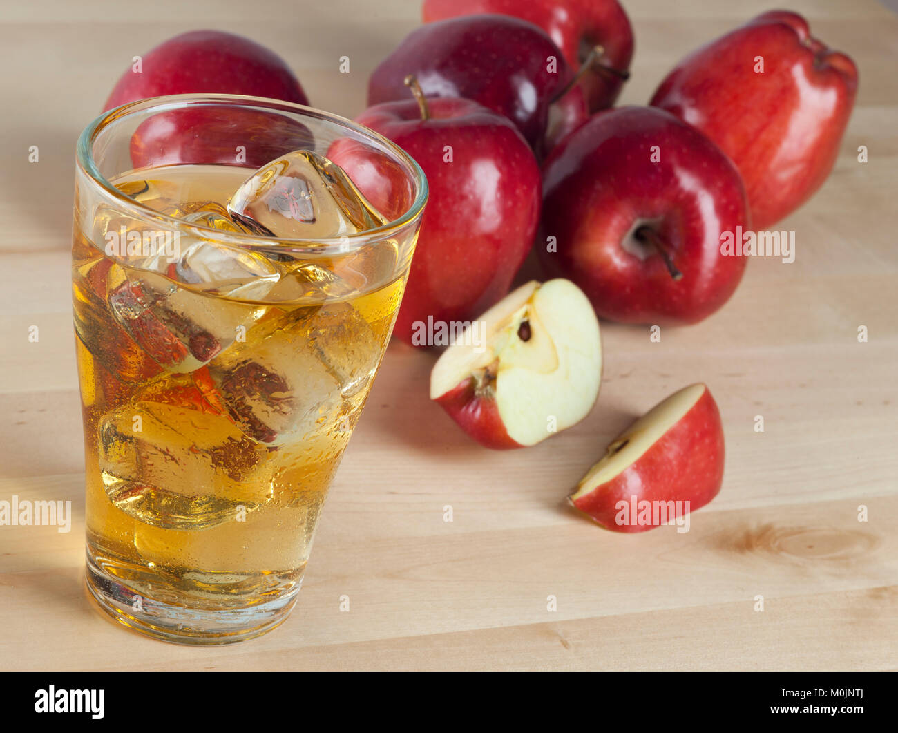 A Glass of Fresh Cold Apple Juice with Ice Beside Apples on A Wooden Table Background Stock Photo