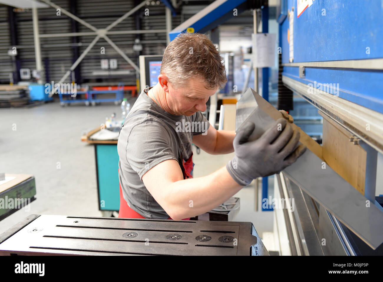 employee operates bending machine in a metalworking company bending of sheet metal for further