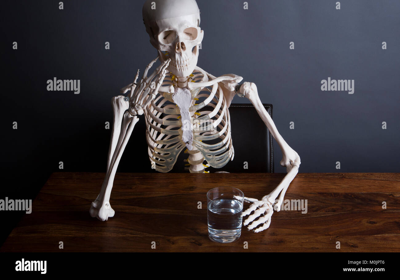 Skelett sits at the table with a glass of water in his hand, Cologne, North Rhine-Westphalia, Germany Germany Germany Stock Photo