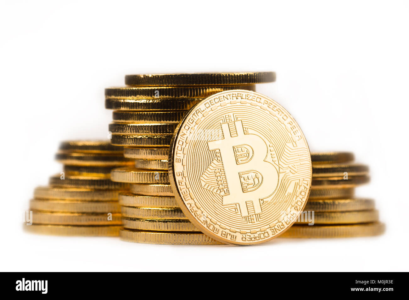 close up golden bitcoin in front of a pile of golden metallic coins isolated on white background Stock Photo