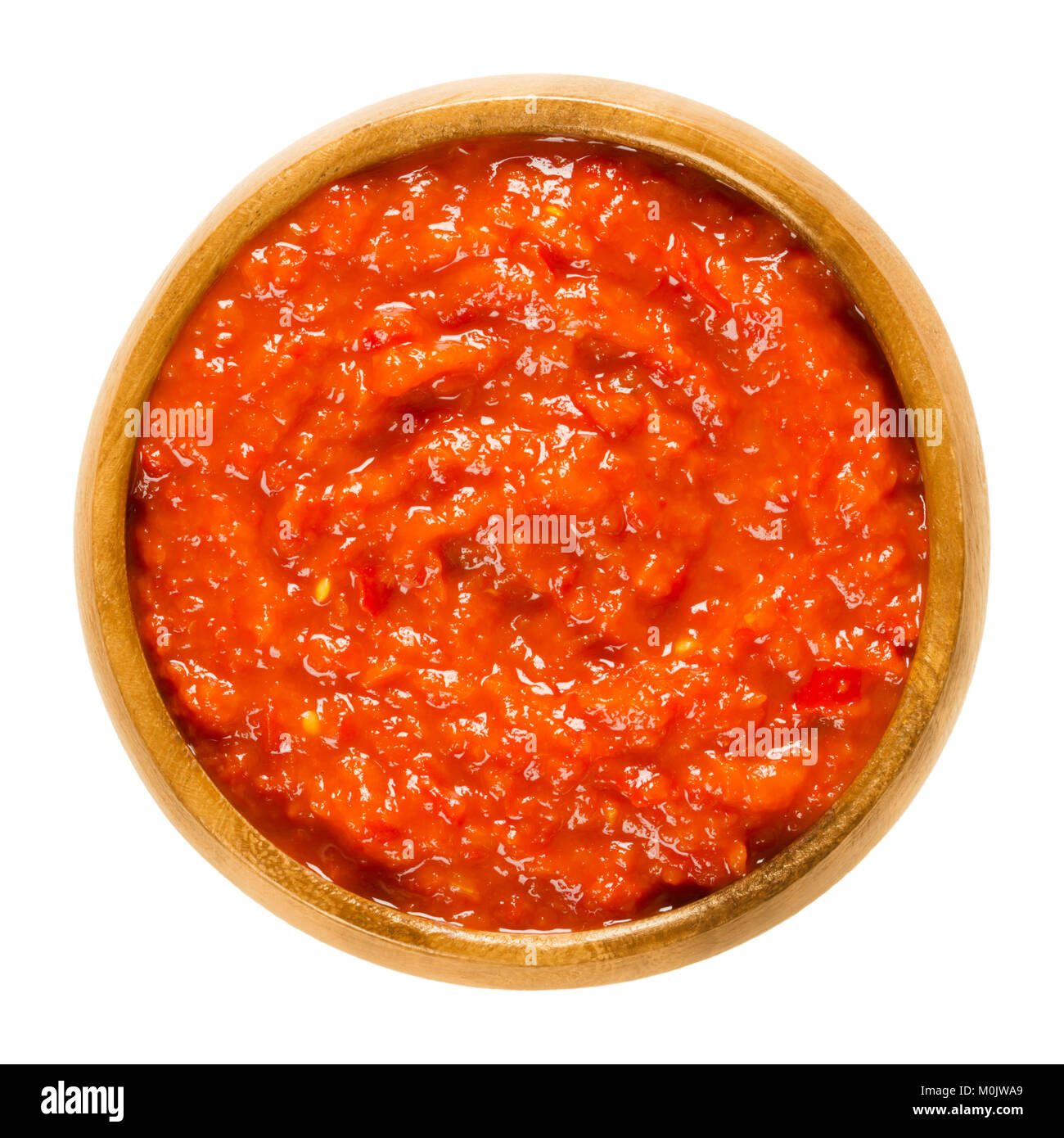 Ajvar in wooden bowl. Condiment made of bell peppers, used in Balkan cuisine. Bread spread or side dish. Also called Serbian salad or vegetable caviar Stock Photo