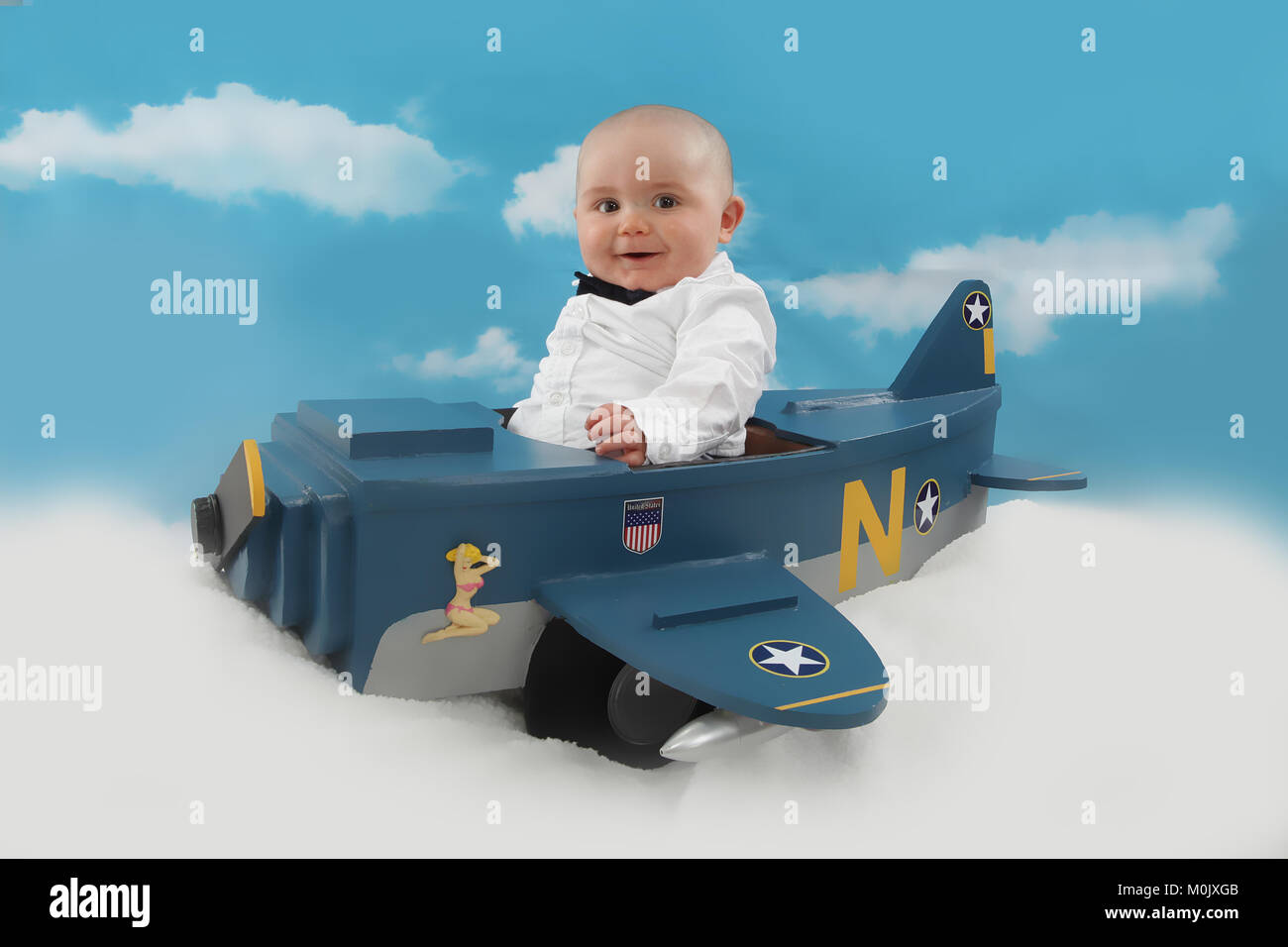 Happy 6 month old baby boy in bow tie flying aeroplane Stock Photo