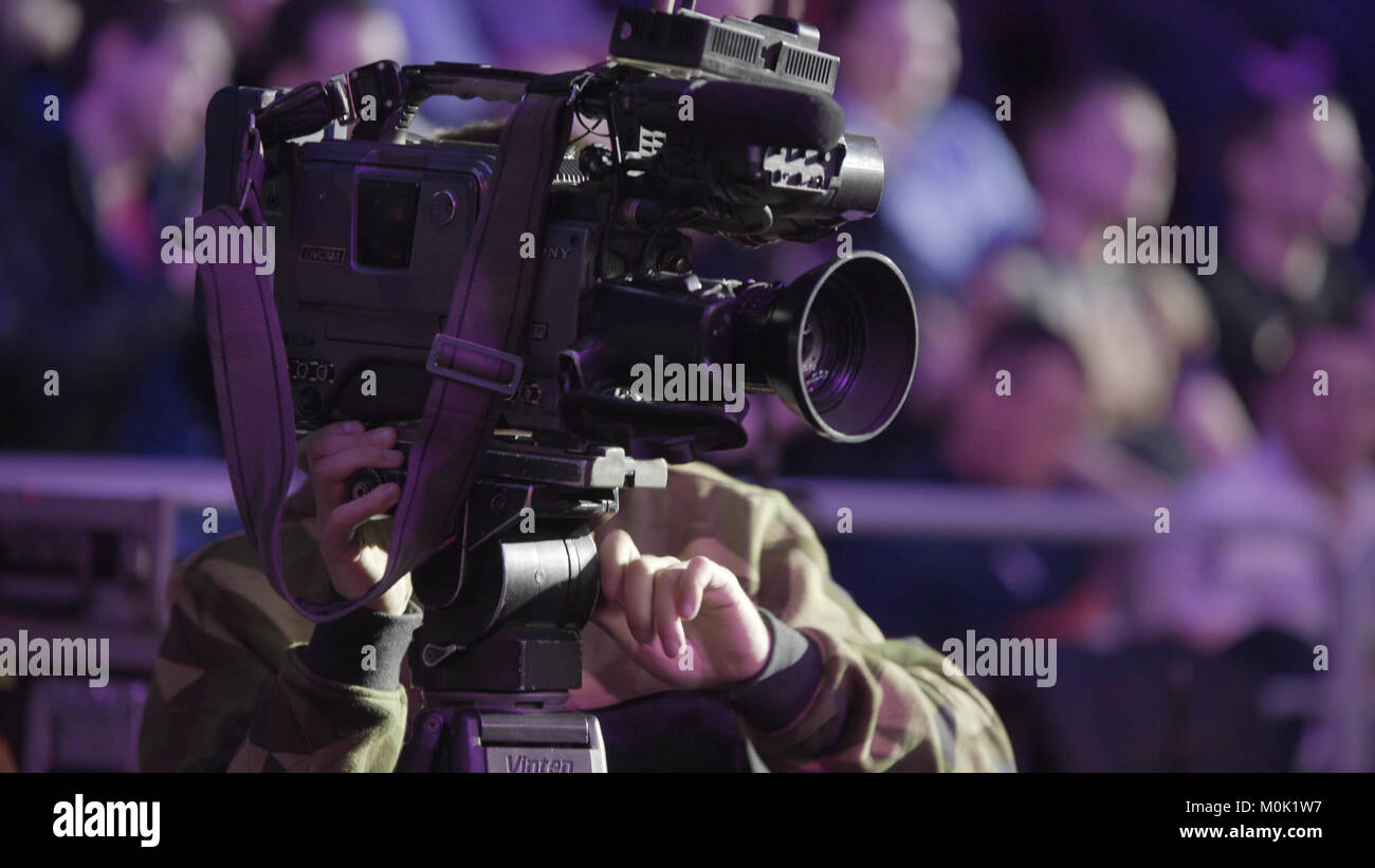 Cameraman using black professional digital video camera. Setup and