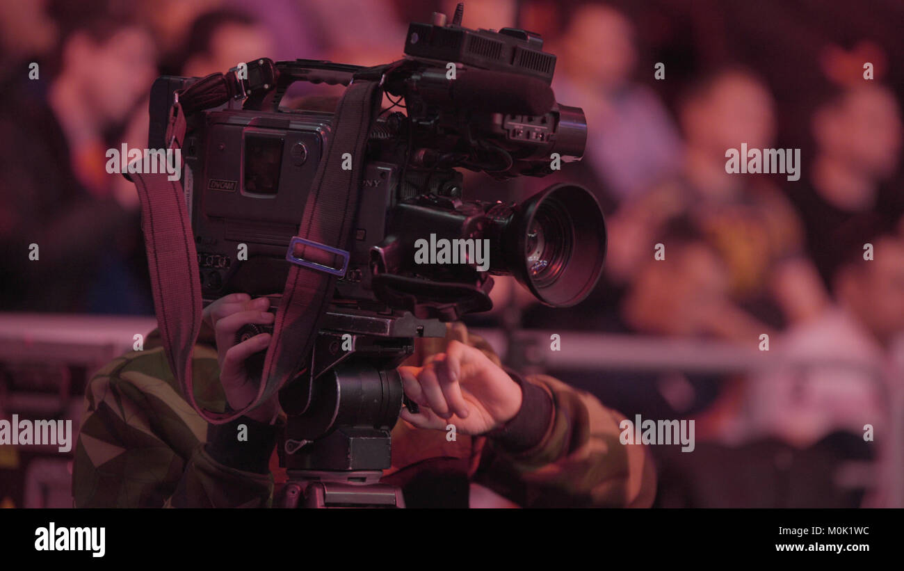 Cameraman using black professional digital video camera. Setup and