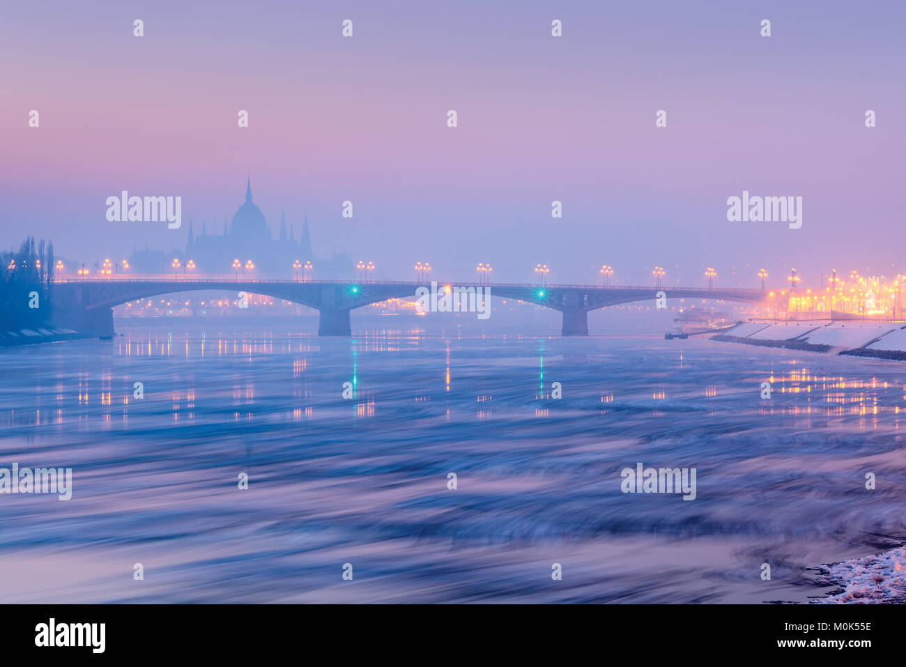 Floes on the river, Margaret bridge, Parliament outline in morning winter haze, Budapest Stock Photo
