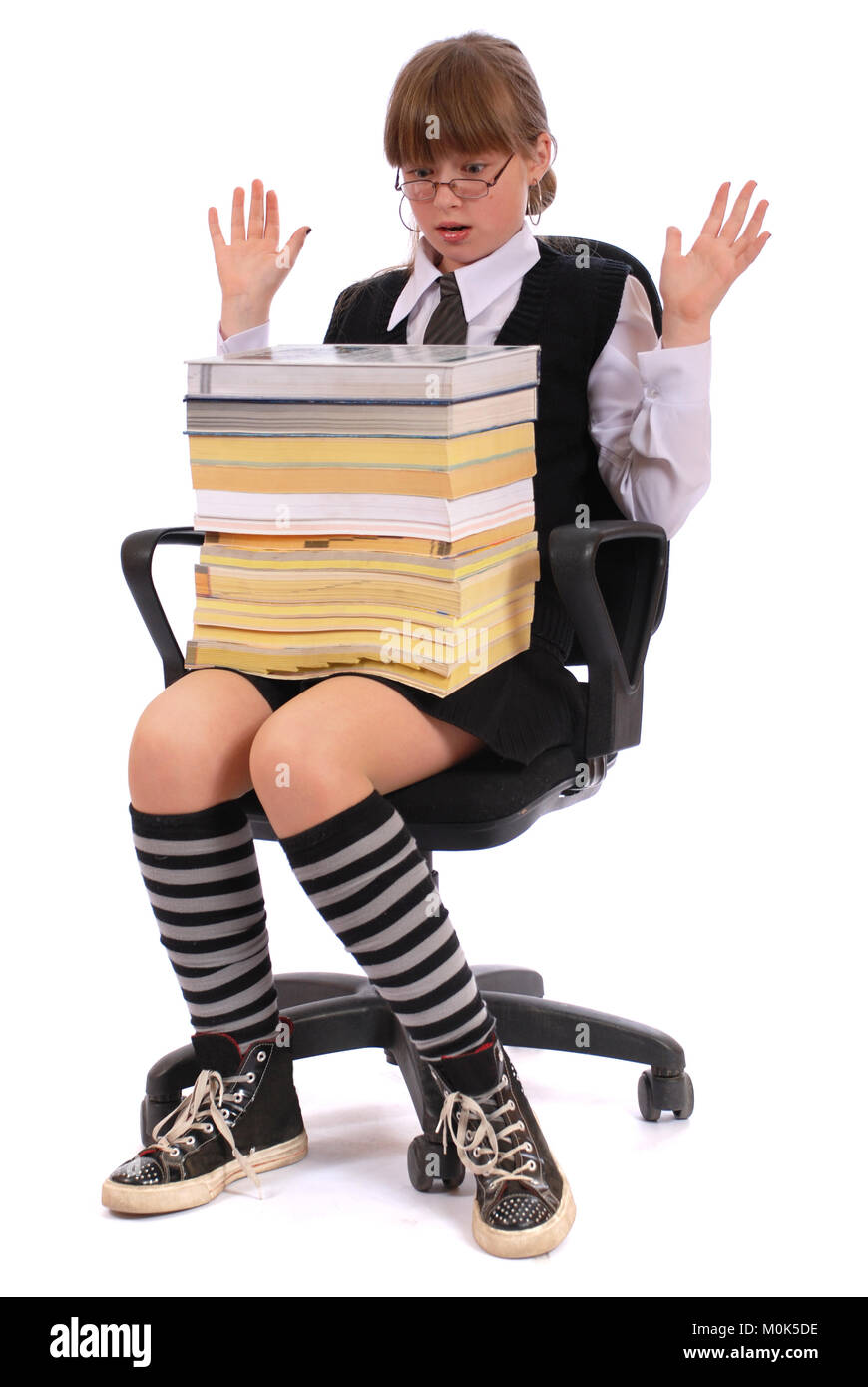 The girl has put the big pile of books on knees. On a white background. Stock Photo