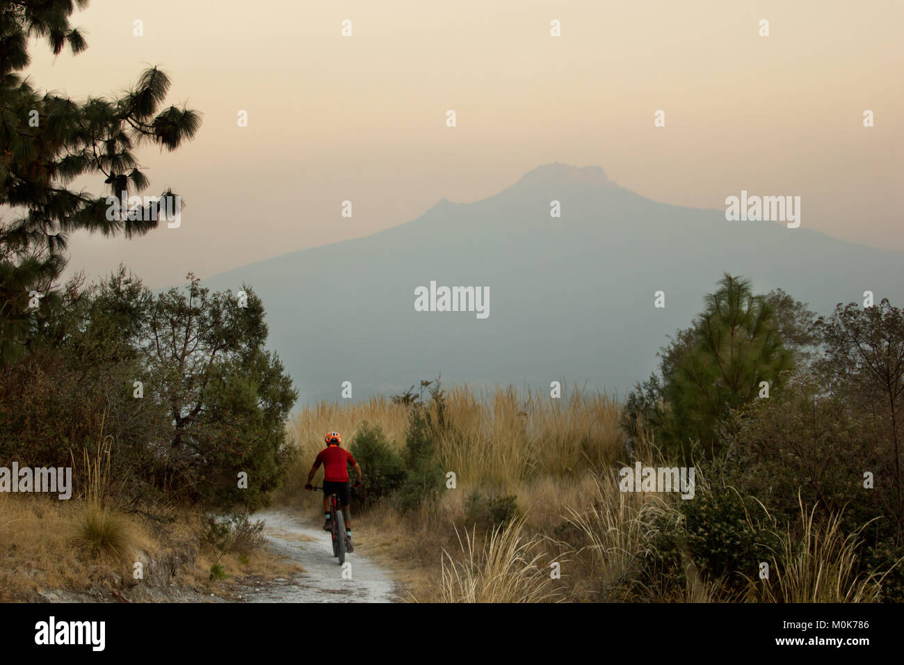 A male mountain bike rider on a trail in Mexico with a Volcano as background Stock Photo
