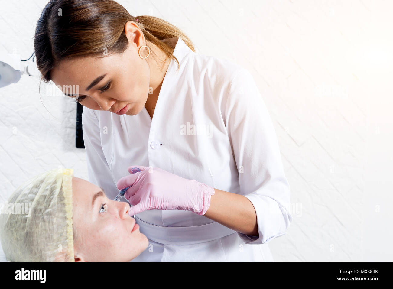 Close-up Young woman doctor cosmetician in white lab coat and sterile ...
