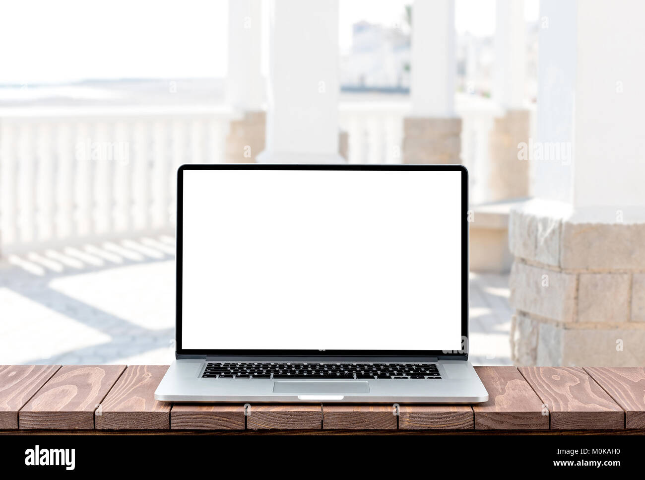 Modern laptop with empty white screen on wooden table against blurred ...