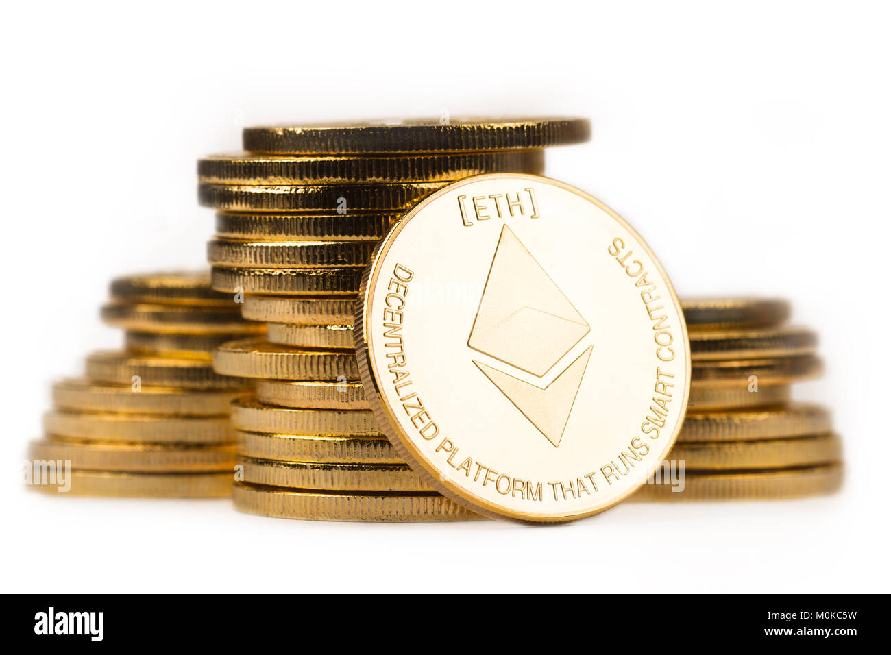 close up golden ethereum in front of a pile of golden metallic coins isolated on white background Stock Photo