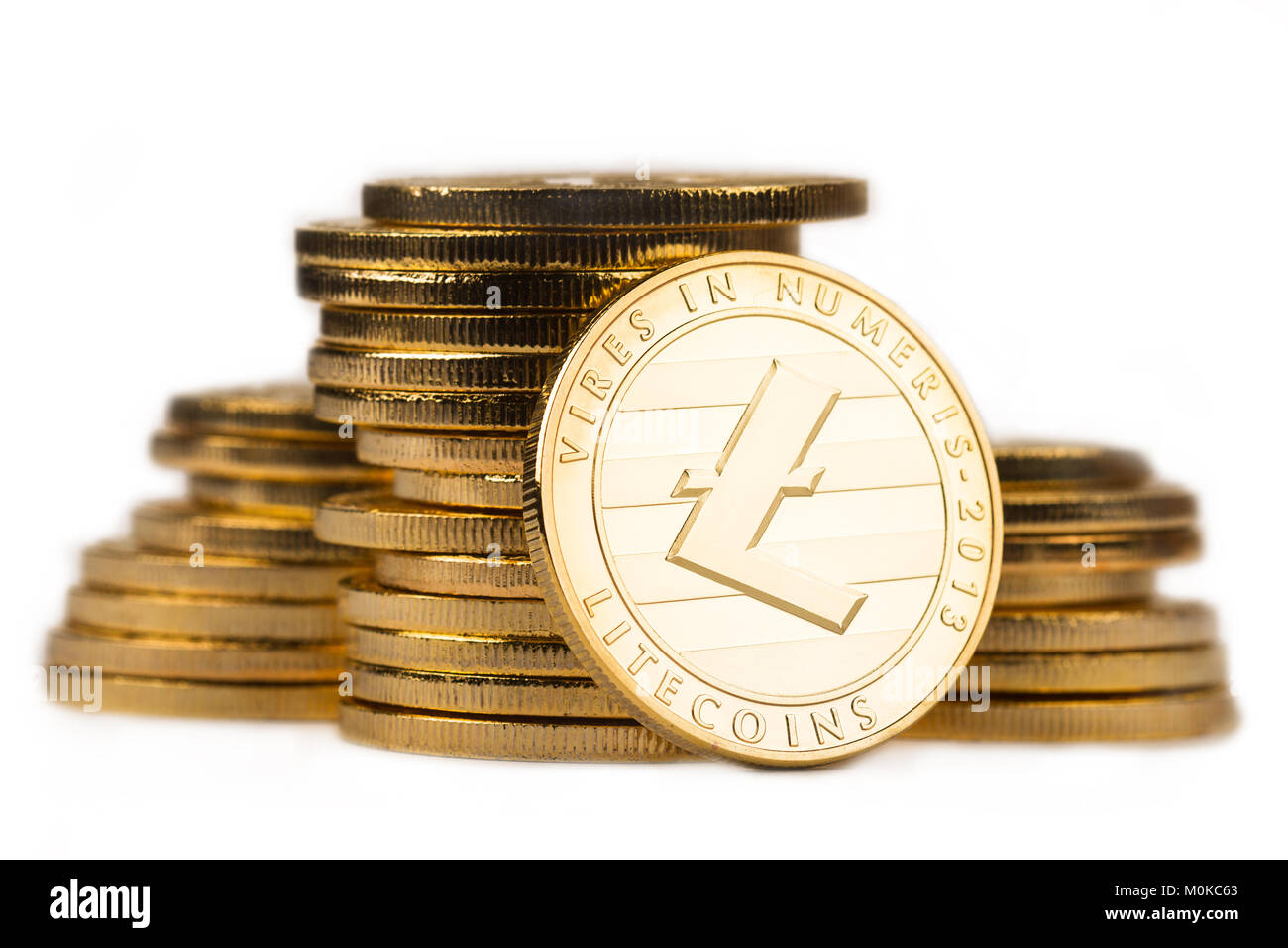 close up golden litecoin in front of a pile of golden metallic coins isolated on white background Stock Photo