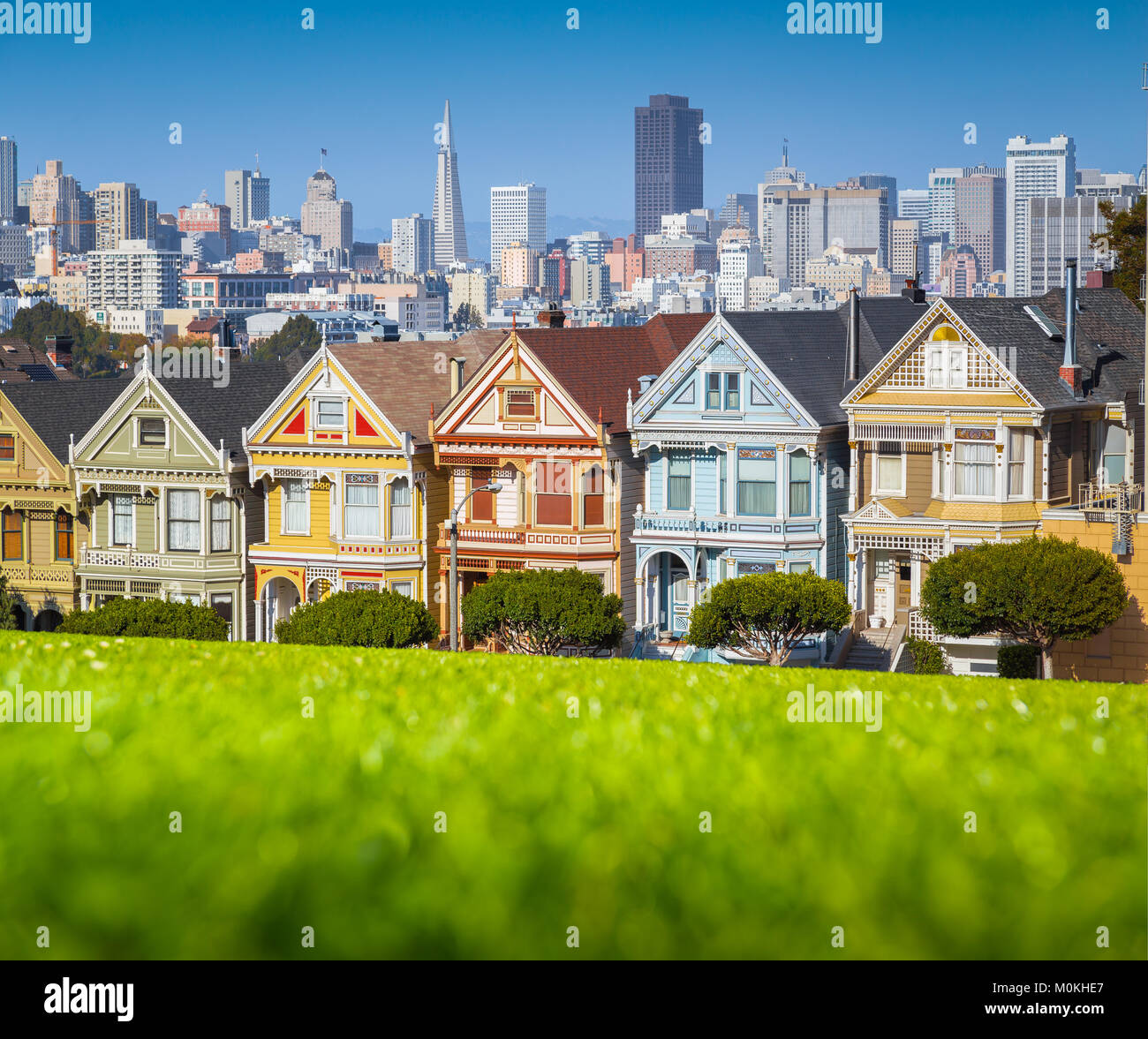 Famous Painted Ladies, a row of colorful Victorian houses located at scenic Alamo Square, with the skyline of San Francisco at sunset, California, USA Stock Photo