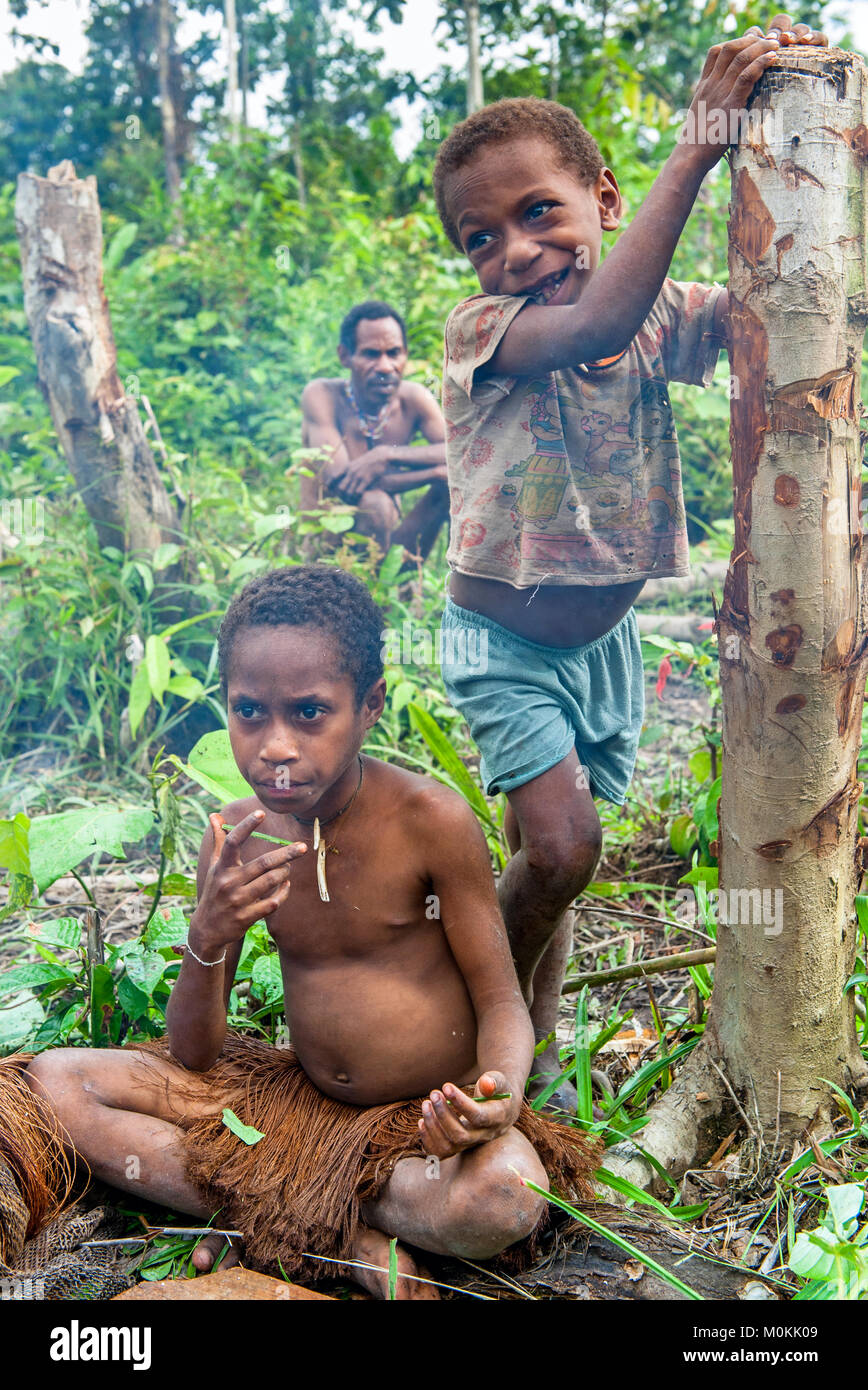 Papuan little children of Korowai tribe in the jungle of New Guinea Island. Stock Photo