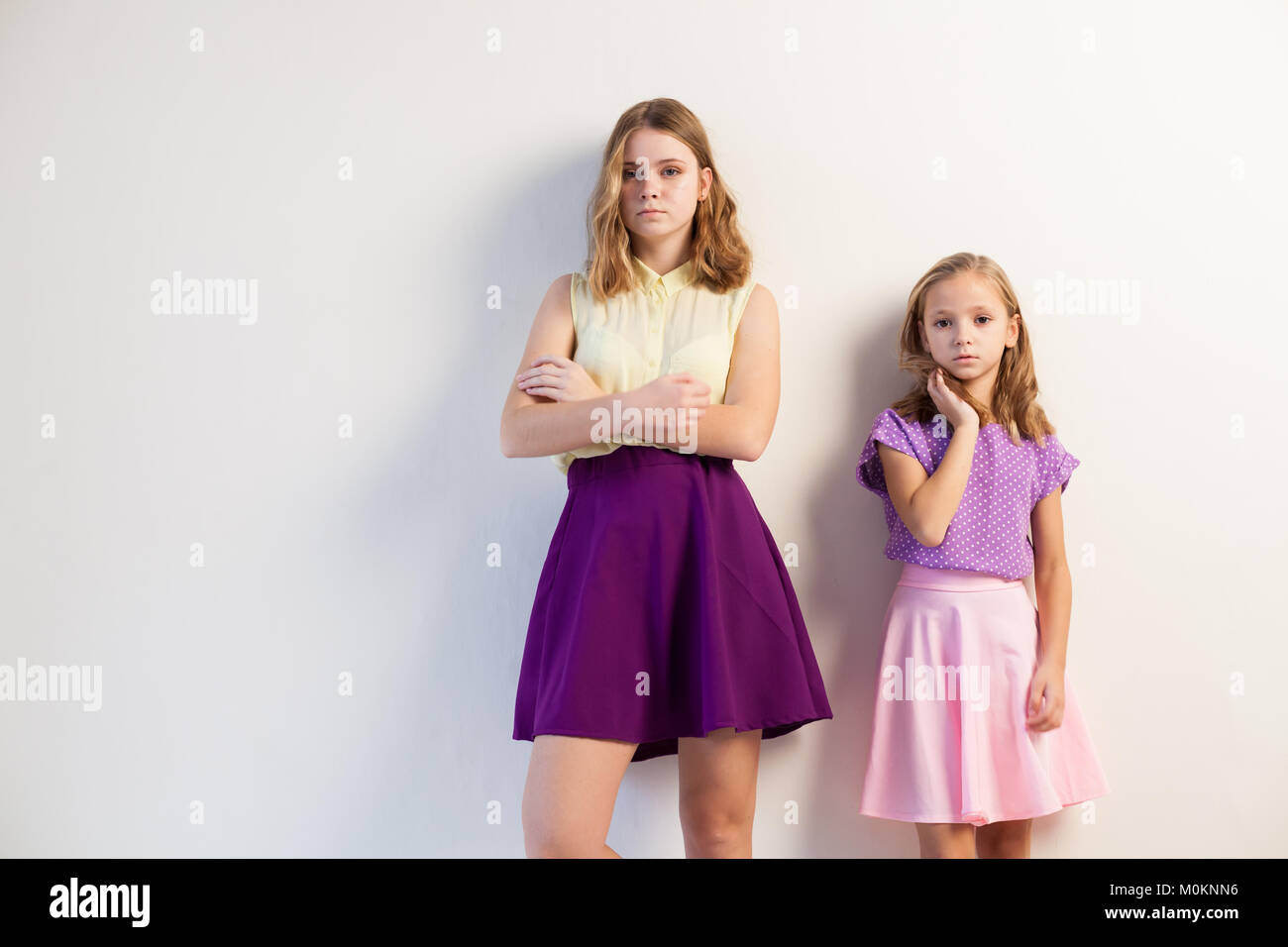two girls sisters in colored dresses posing Stock Photo - Alamy