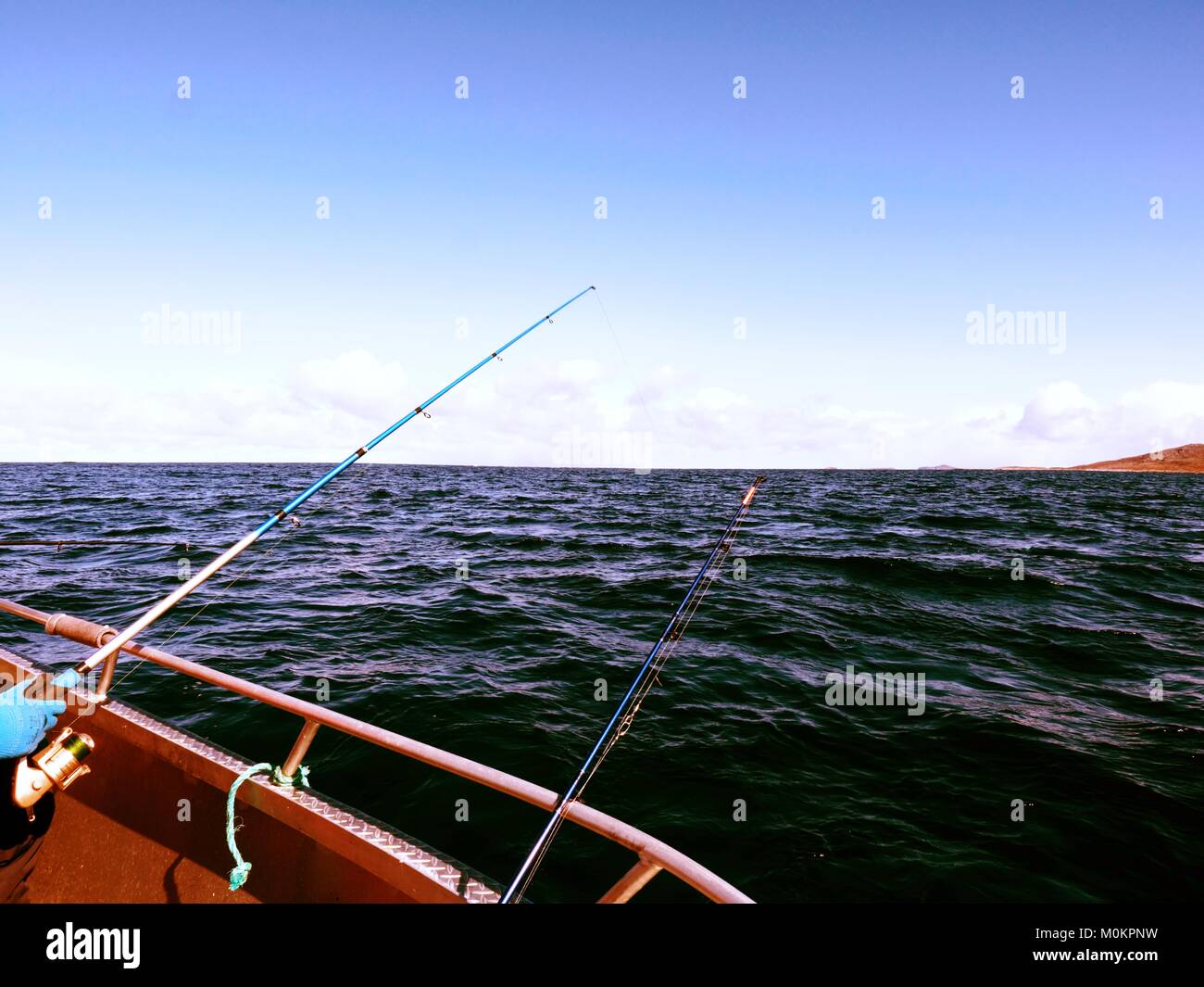 Fishing boat with fishing rods floating in open sea. Background beautiful  sky. Sport sea fishing Stock Photo - Alamy