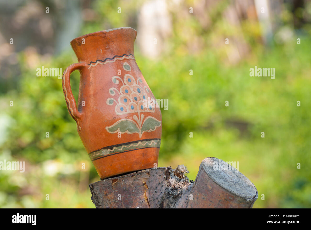 Ancient Ukrainian clay pot standing on a cut tree in summer garden Stock Photo