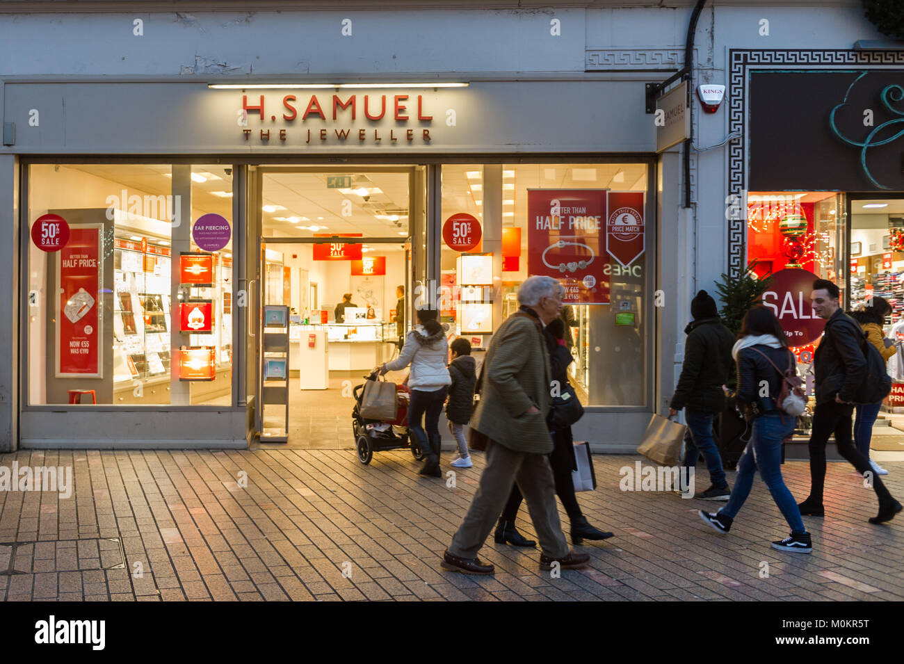 H. Samuel Jewellers shop on Patrick Street, Cork, Ireland with shoppers at dusk in the January sales. Stock Photo
