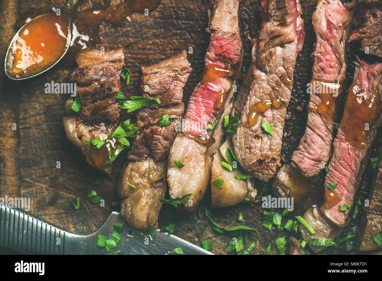 Flat-lay of grilled medium rare ribeye beef steak cut into peices on ...