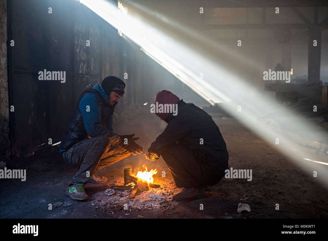 Belgrade, Serbia - January 7, 2017: Refugees try to warm in an abandoned hangar near the main train station. The temperature is minus 12 degrees celsi Stock Photo