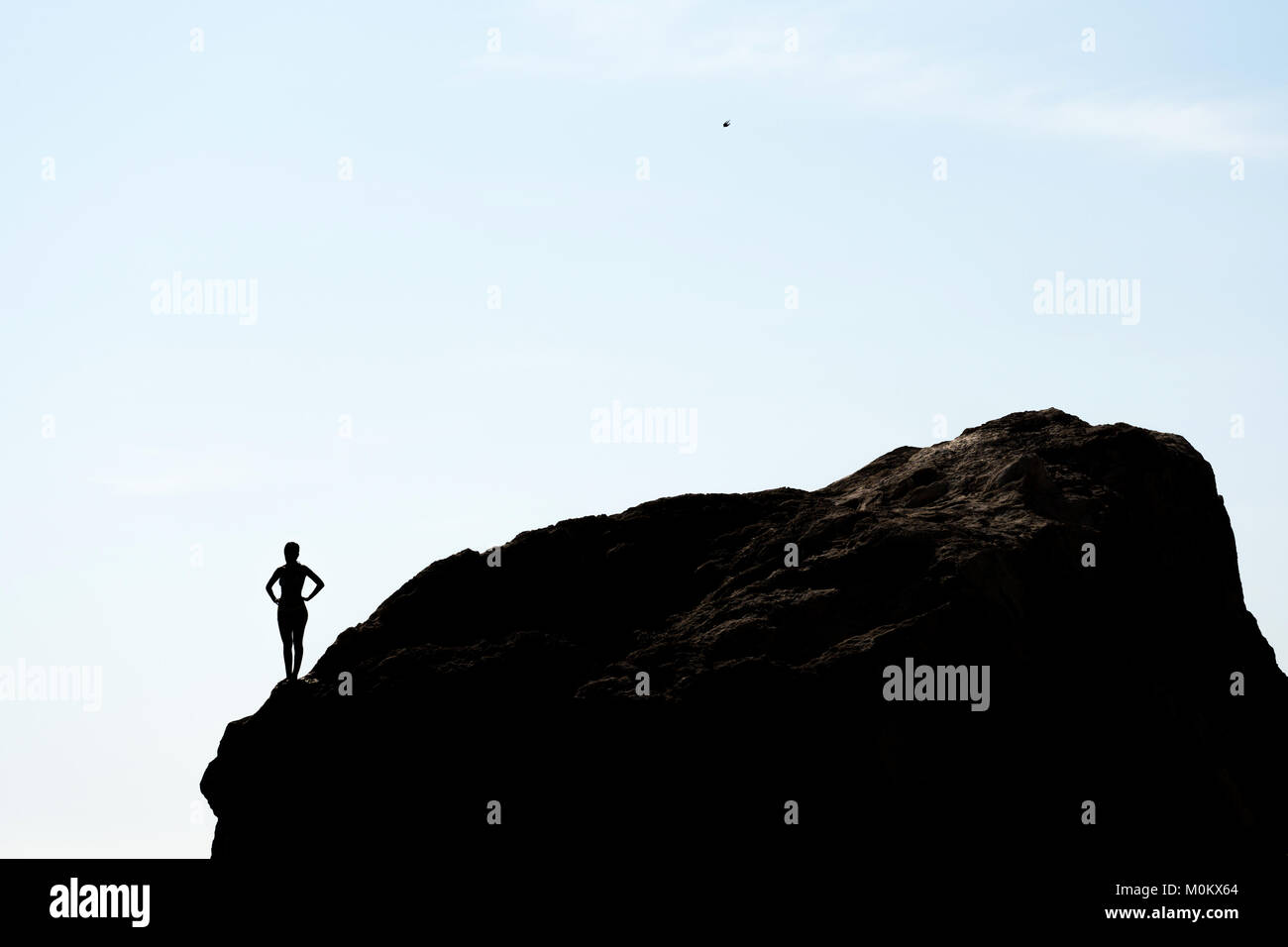 Silhouette of a girl standing on a rock Stock Photo