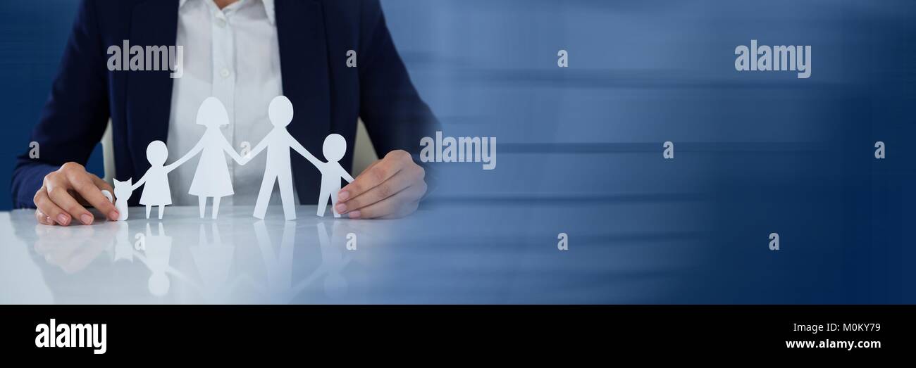 Paper Cut Out family in business persons hands Stock Photo