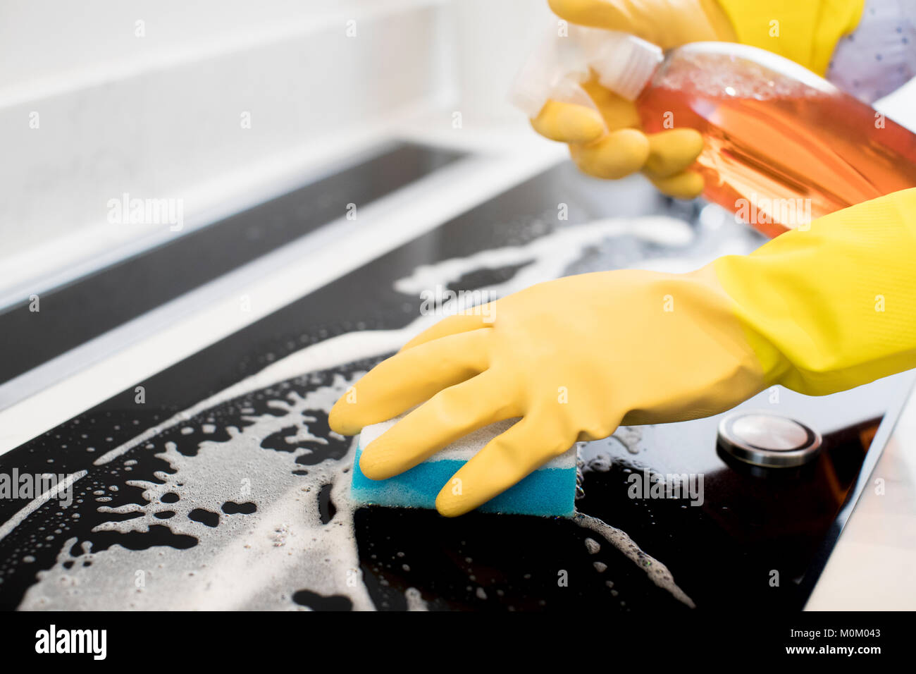 Close Up Of Woman Wearing Rubber Gloves Cleaning Kitchen Hob Stock Photo