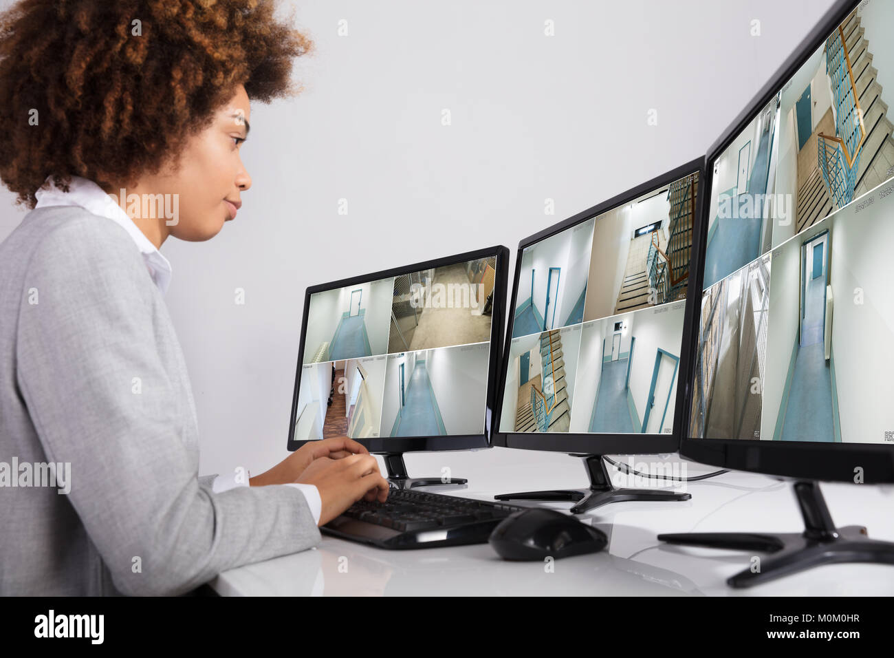 Businesswoman Looking At Multiple Camera Footage In Office Stock Photo