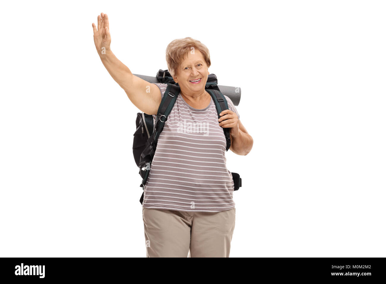 Elderly female hiker waving at the camera isolated on white background Stock Photo