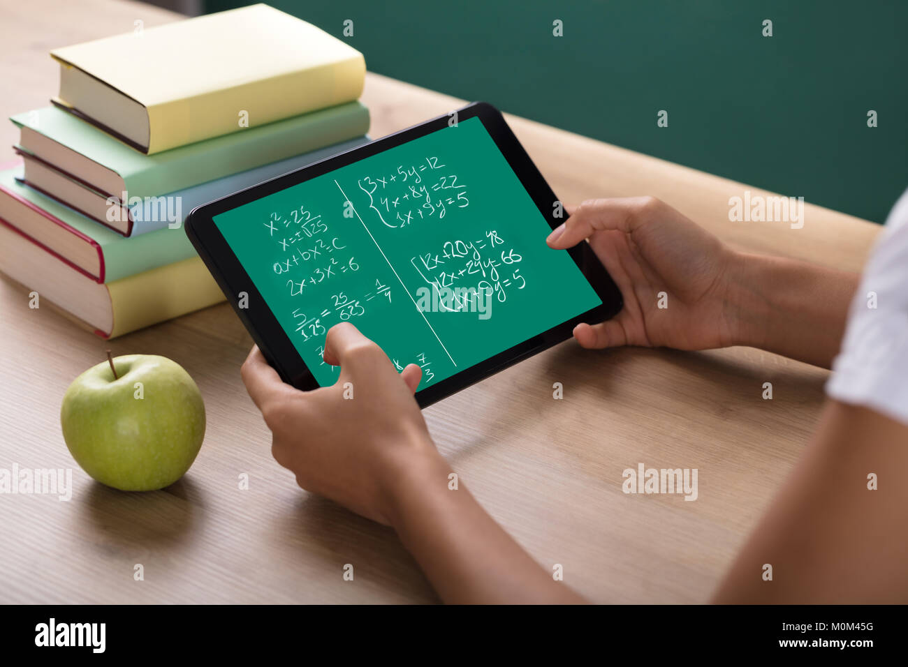 Close-up Of Human Hand Solving Math Problems On Digital Tablet In Classroom Stock Photo