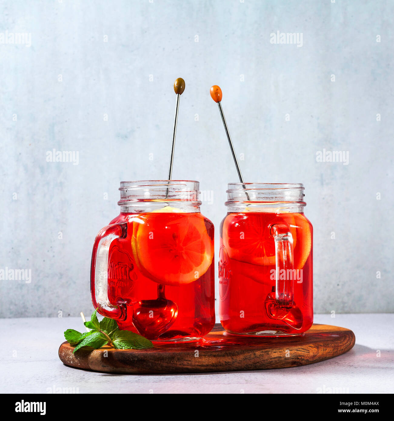 chilled karkade tea with lemon on a wooden stand on a stone table and background. antioxidants, spasmolytic, diuretic, antipyretic properties. Stock Photo