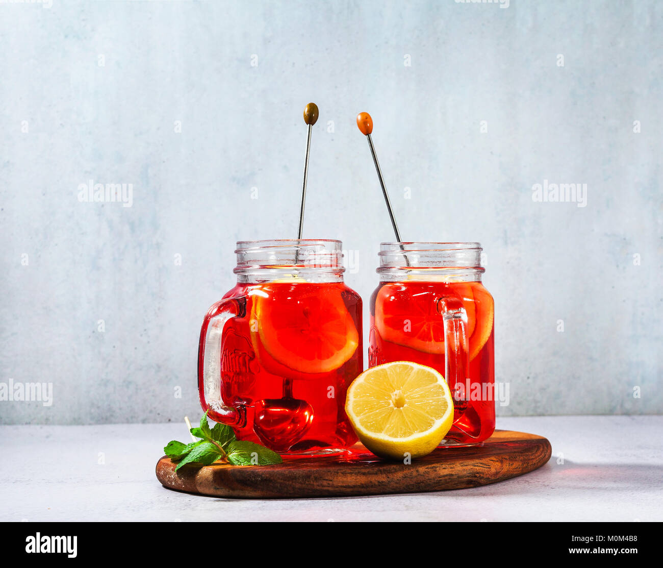 chilled karkade tea with lemon on a wooden stand on a stone table and background. antioxidants, spasmolytic, diuretic, antipyretic properties. Stock Photo