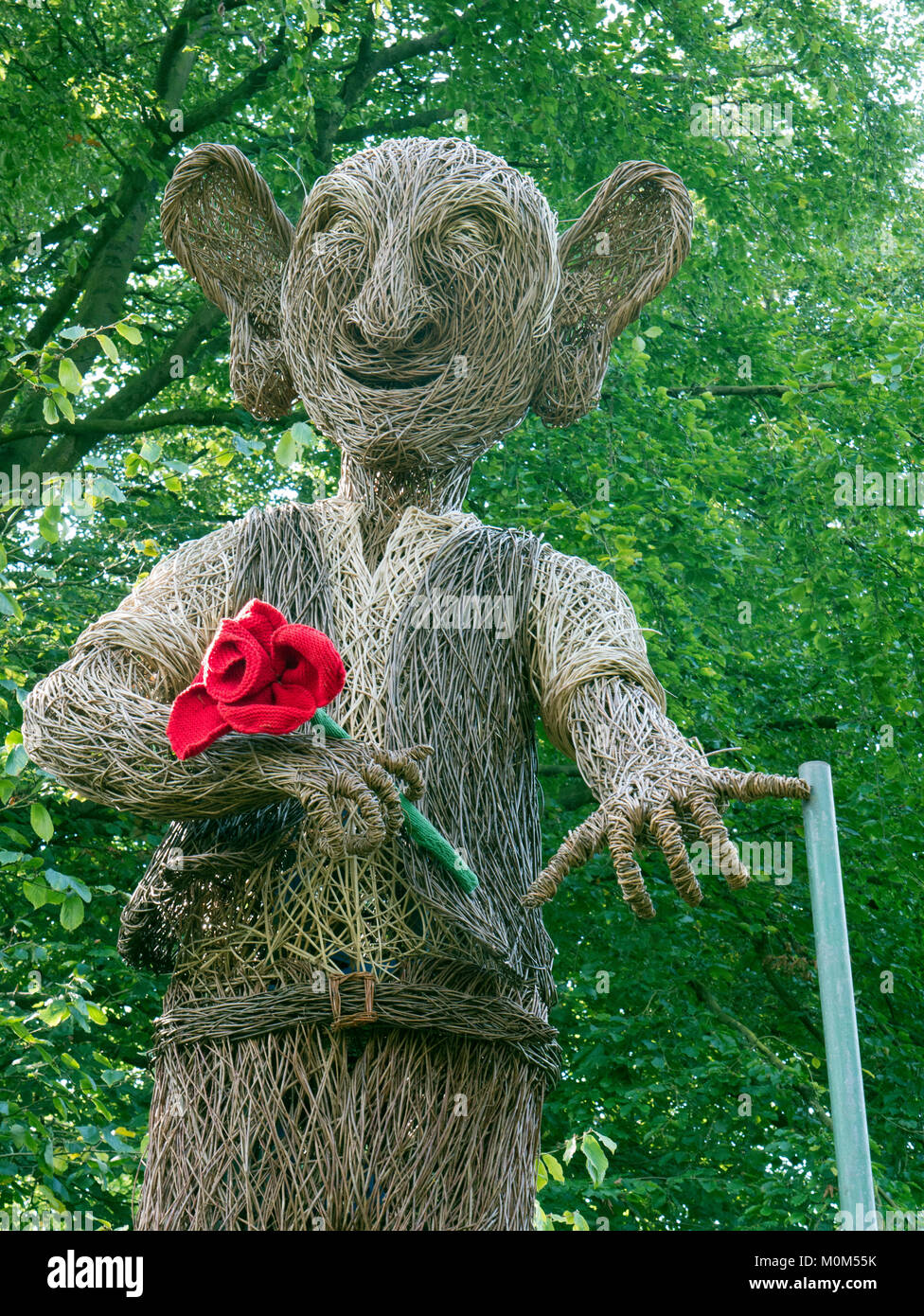 Willow sculpture of BFG (big friendly giant) ,holding a knitted red rose, at RHS garden Harlow Carr, Yorkshire Stock Photo