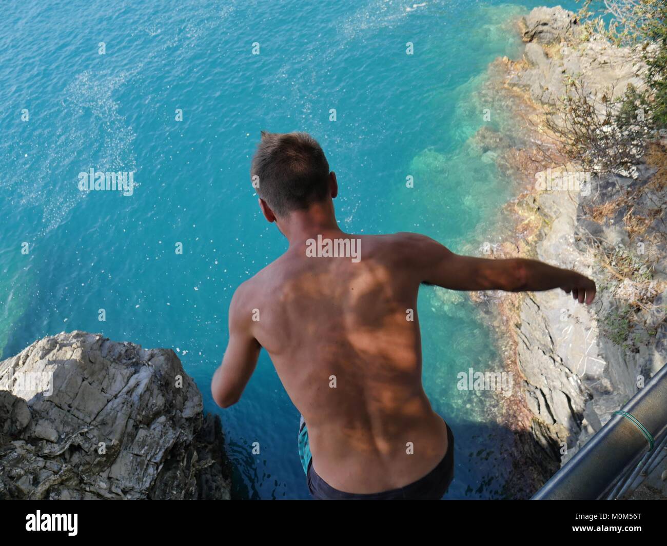 Man jumping into sea from high cliff Manarola Italy Stock Photo