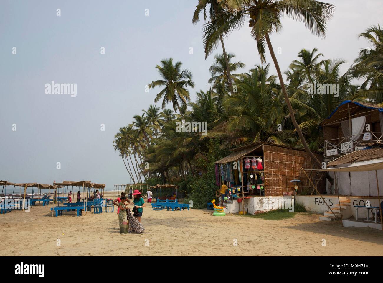 India,Goa,Morjim beach,woman seiling saris to a tourist in the beach lined with shops and coconut trees Stock Photo