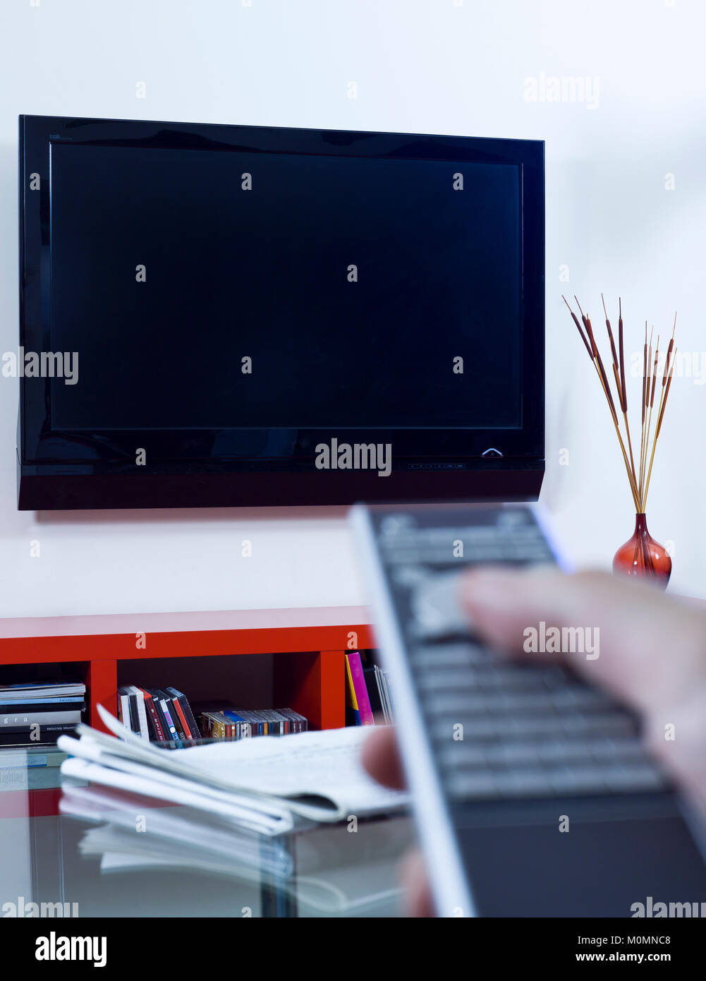 Hand Pointing A Remote Control To A TV Set in a home environment Stock Photo