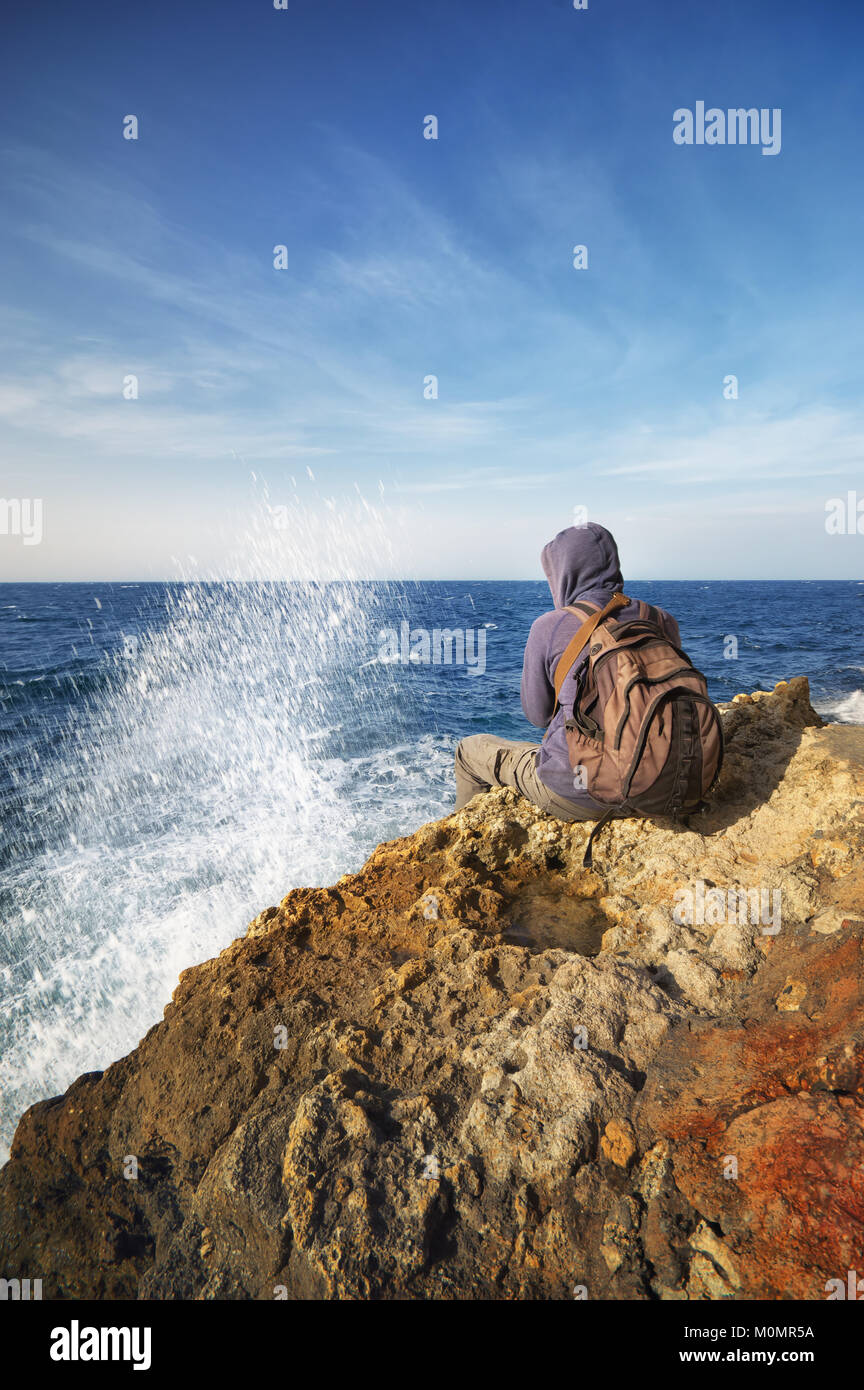 man admires the scenery on the edge cliff of the sea shore Stock Photo