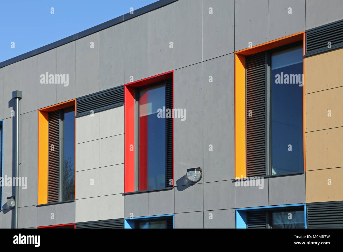 Cladding detail of a new London primary school showing brightly coloured window reveals and grey wall panels. Stock Photo