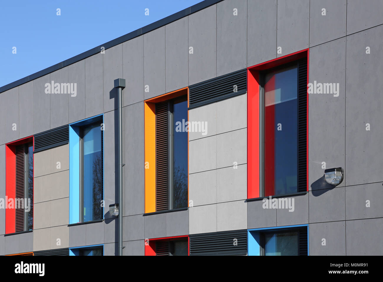 Cladding detail of a new London primary school showing brightly coloured window reveals and grey wall panels. Stock Photo