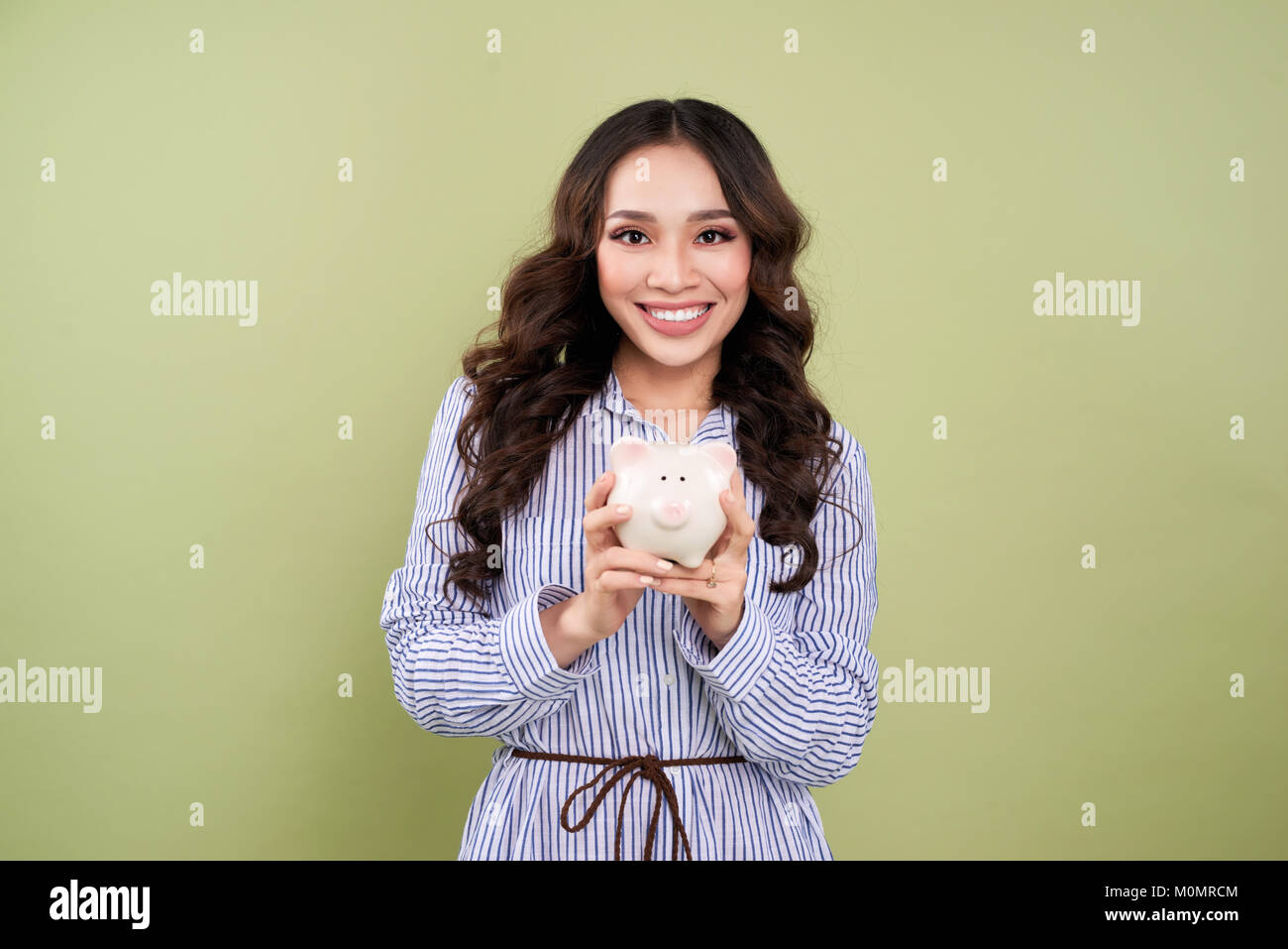 Young woman with a piggy bank on a green background Stock Photo - Alamy