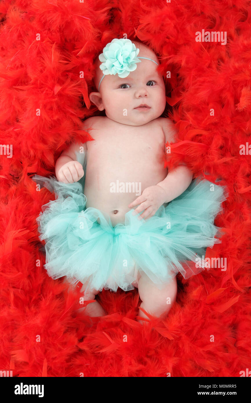 baby in pile of red feather bed Stock Photo Alamy